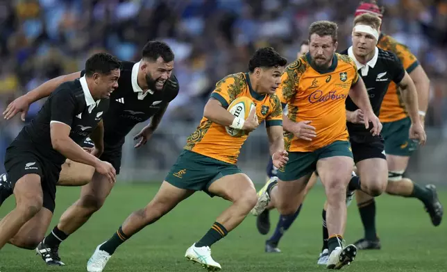 Australia's Noah Lolesio, center, looks make break against New Zealand during their rugby union test match in Sydney, Saturday, Sept. 21, 2024. (AP Photo/Rick Rycroft)