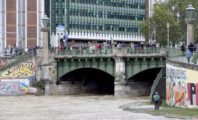 People watch the junction of river Wien and Donaukanal channel as they flood their banks in central Vienna, Austria, Sunday, Sept. 15, 2024. (AP Photo/Heinz-Peter Bader)