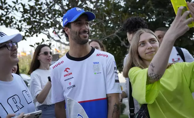 RB driver Daniel Ricciardo of Australia poses for a selfie with fans in the paddock at the Baku circuit, in Baku, Azerbaijan, Thursday, Sept.12, 2024. The Formula One Grand Prix will be held on Sunday. (AP Photo/Sergei Grits)
