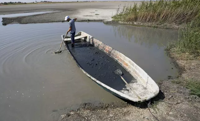 A man collects mud to be used in medical therapy from the Rusanda salty lake that has dried out completely, near Melenci, Serbia, Wednesday, Sept. 4, 2024. Experts say the summer of 2024 in the Balkans was the hottest since measurements started more than 130 years ago. (AP Photo/Darko Vojinovic)