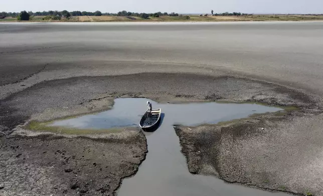 A man collects mud that is used in medical therapy at the dried out Rusanda salty lake, near Melenci, Serbia, Wednesday, Sept. 4, 2024. Experts say the summer of 2024 in the Balkans was the hottest since measurements started more than 130 years ago. (AP Photo/Darko Vojinovic)