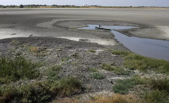 A man collects mud that is used in medical therapy at the dried out Rusanda salty lake, near Melenci, Serbia, Wednesday, Sept. 4, 2024. Experts say the summer of 2024 in the Balkans was the hottest since measurements started more than 130 years ago. (AP Photo/Darko Vojinovic)