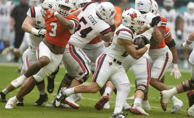 Ball State running back Vaughn Pemberton, right, runs past Miami defensive lineman Akheem Mesidor (3) during the first half of an NCAA football game, Saturday, Sept. 14, 2024, in Miami Gardens, Fla. (AP Photo/Lynne Sladky)