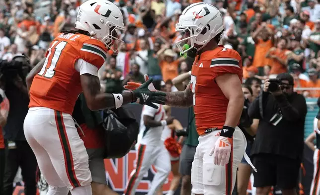 Miami wide receiver Samuel Brown (11) congratulates wide receiver Xavier Restrepo (7) after Restrepo scored a touchdown during the first half of an NCAA football game, Saturday, Sept. 14, 2024, in Miami Gardens, Fla. (AP Photo/Lynne Sladky)