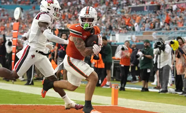 Miami wide receiver Xavier Restrepo (7) scores a touchdown past Ball State defensive back Jordan Coleman, left, during the first half of an NCAA football game, Saturday, Sept. 14, 2024, in Miami Gardens, Fla. (AP Photo/Lynne Sladky)