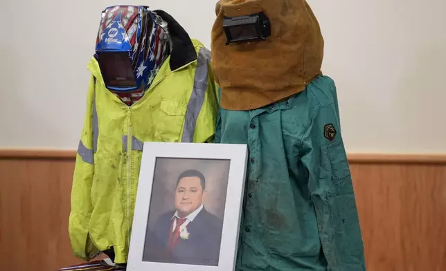 A portrait of Miguel Luna, a worker who died during the collapse of Baltimore's Francis Scott Key Bridge, is displayed among articles of his welding gear, Tuesday, Sept. 17, 2024, during a press conference in Baltimore. (AP Photo/Stephanie Scarbrough)