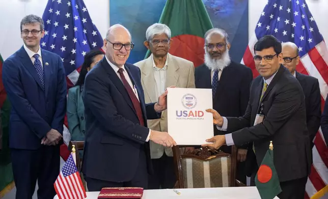 Reed J. Aeschliman, USAID Mission Director for Bangladesh, front left, and A. K. M. Shahabuddin, Additional Secretary, Ministry of Finance, Bangladesh, pose for a photograph with other officials after signing the 6th amendment of 'The Development Objective Grant Agreement (DOAG)' in Dhaka, Bangladesh, Sunday, Sept. 15, 2024. (AP Photo/Rajib Dhar)