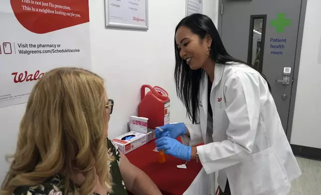 Anh Nguyen prepares to administer a COVID-19 vaccine for Kelly Vazquez at a pharmacy in New York, Tuesday, Sept. 24, 2024. (AP Photo/Mary Conlon)