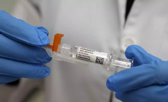 A pharmacist holds a COVID-19 vaccine at a pharmacy in New York, Tuesday, Sept. 24, 2024. (AP Photo/Mary Conlon)