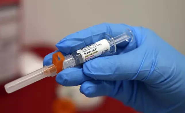 A pharmacist holds a COVID-19 vaccine at a pharmacy in New York, on Tuesday, Sept. 24, 2024. (AP Photo/Mary Conlon)