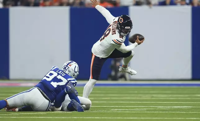 Chicago Bears quarterback Caleb Williams (18) scrambles under pressure from Indianapolis Colts defensive end Laiatu Latu (97) and linebacker Zaire Franklin (44) during the first half of an NFL football game Sunday, Sept. 22, 2024, in Indianapolis. (AP Photo/Michael Conroy)