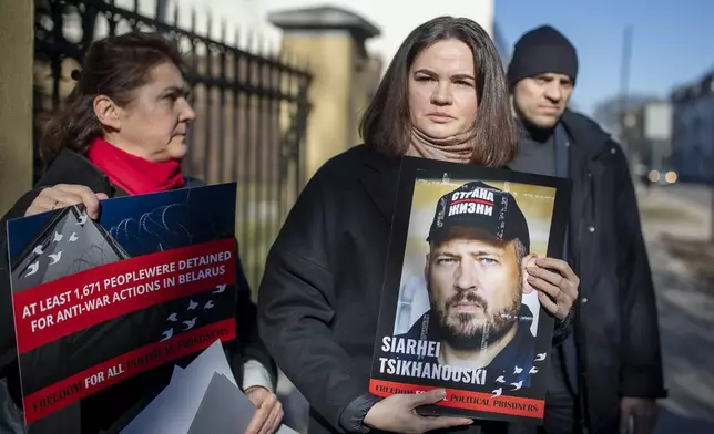 FILE - Belarusian opposition leader Sviatlana Tsikhanouskaya, center, holds a portrait of her jailed husband, Siarhei Tsikhanouski, at a protest outside the Belarus Embassy, in Vilnius, Lithuania, on March 8, 2024, demanding freedom for political prisoners. (AP Photo/Mindaugas Kulbis, File)