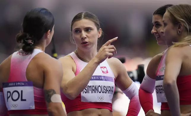 FILE – Former Belarusian athlete Krystsina Tsimanouskaya, who sought political asylum in Poland three years ago, talks with teammates following their women's 4x100-meter relay heat at the Paris Olympics, on Aug. 8, 2024, in Saint-Denis, France. (AP Photo/Petr David Josek, File)