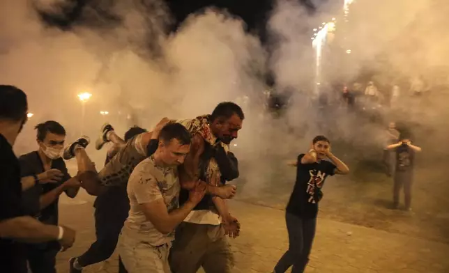 FILE - Protesters carry a man injured during clashes with police amid demonstrations in Minsk, Belarus, on Aug. 10, 2020. (AP Photo, File)