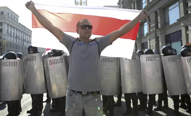 FILE – A protester holds a red-and-white flag that was a symbol of the opposition in front of a police line during an anti-government demonstration in Minsk, Belarus, on Aug. 30, 2020.(AP Photo, File)