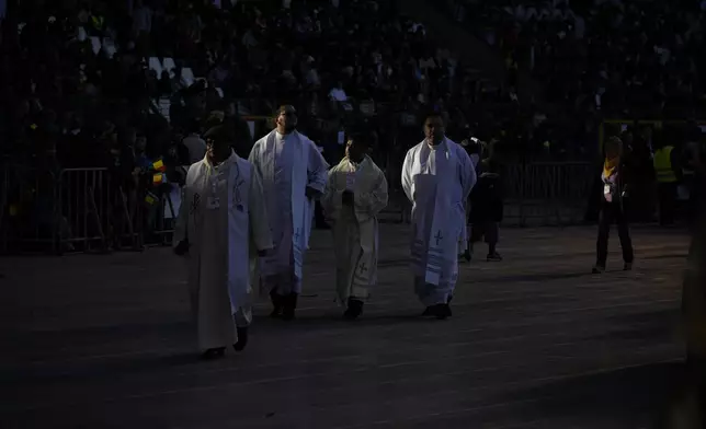 Priests wait for the start of a mass presided by Pope Francis at King Baudouin Stadium, in Brussels Sunday, Sept. 29, 2024. (AP Photo/Andrew Medichini)