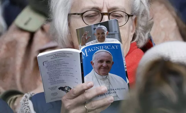 A faithful reads a book as Pope Francis presides the holy mass, at the King Baudouin stadium in Brussels, Belgium, Sunday, Sept. 29, 2024. (AP Photo/Omar Havana)