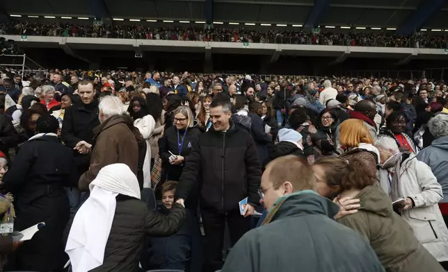 A faithful exchange a sign of peace as Pope Francis presides the holy mass , at the King Baudouin stadium in Brussels, Belgium, Sunday, Sept. 29, 2024. (AP Photo/Omar Havana)