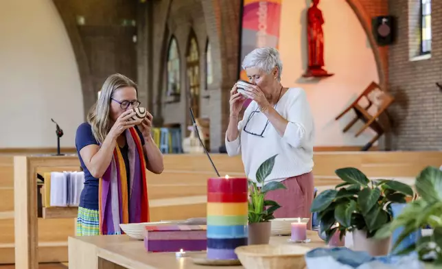 Laywomen Nancy Speeckaert, left, and Marijke Devaddere drink wine after the Eucharistic Prayer during a service they led at the Don Bosco church in Buizingen, Belgium, Sunday, Sept. 8, 2024. (AP Photo/Geert Vanden Wijngaert)