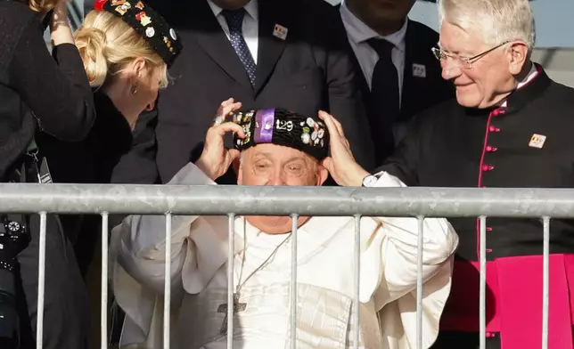 Pope Francis wears a traditional hat at the end of his meeting with students of the Louvain Catholic University in Ottignies-Louvain-la-Neuve, Belgium, Saturday, Sept. 28, 2024. (AP Photo/Geert Vanden Wijngaert)