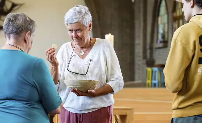 Laywoman Marijke Devaddere, center, hands over a host to a parishioner at the Don Bosco church in Buizingen, Belgium, Sunday, Sept. 8, 2024. (AP Photo/Geert Vanden Wijngaert)