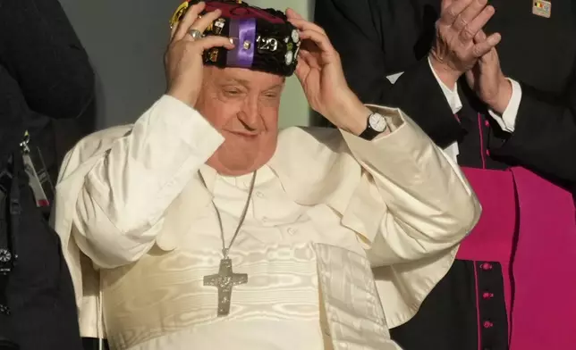 Pope Francis wears a traditional hat at the end of his meeting with students of the Louvain Catholic University in Ottignies-Louvain-la-Neuve, Belgium, Saturday, Sept. 28, 2024. (AP Photo/Andrew Medichini)