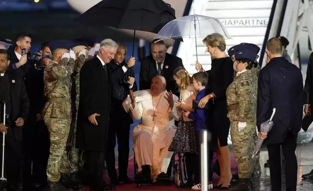 Pope Francis arrives flanked by Queen Mathilde of Belgium and King Philippe of Belgium at the Melsbroek air base in Steenokkerzeel, near Brussels, on the first day of his four-day visit to Luxembourg and Belgium, Thursday, Sept. 26, 2024. (AP Photo/Andrew Medichini)