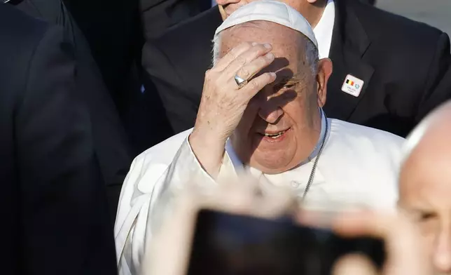 Pope Francis covers his eyes from the sun as he leaves at the end of his meeting with students of the Louvain Catholic University in Ottignies-Louvain-la-Neuve, Belgium, Saturday, Sept. 28, 2024. (AP Photo/Geert Vanden Wijngaert)