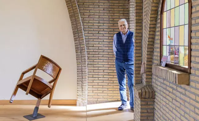 Rik Deville, a retired priest, poses next to a church chair with a message written in Dutch saying "No More Abuse" at the Don Bosco church in Buizingen, Belgium, Sunday, Sept. 8, 2024. (AP Photo/Geert Vanden Wijngaert)