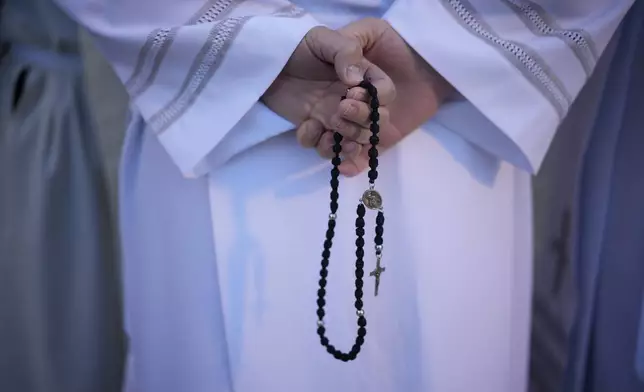 A priest holds a rosary prior to the start of a mass presided by Pope Francis at King Baudouin Stadium, in Brussels Sunday, Sept. 29, 2024. (AP Photo/Andrew Medichini)