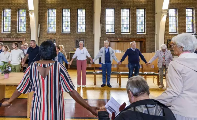 Laywoman Marijke Devaddere, center left, and Rik Deville, a retired priest, center right, together with other parishioners participate in a service at the Don Bosco church in Buizingen, Belgium, Sunday, Sept. 8, 2024. (AP Photo/Geert Vanden Wijngaert)