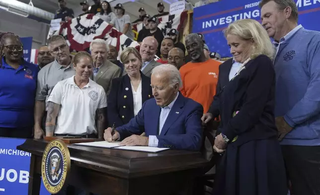 President Joe Biden participates in a signing ceremony after speaking to labor union members about his Investing in America agenda during a visit to the U.A. Local 190 Training Center in Ann Arbor, Mich., Friday, Sep. 6, 2024, as Rep. Debbie Dingell, D-Mich., right, looks on. (AP Photo/Manuel Balce Ceneta)