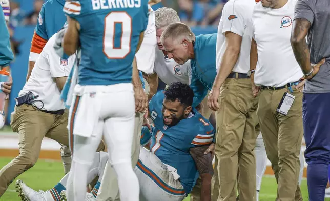 Miami Dolphins quarterback Tua Tagovailoa (1) is assisted after an injury in the third quarter of an NFL football game against the Buffalo Bills in Miami Gardens, Fla., Thursday, Sept. 12, 2024. (Al Diaz/Miami Herald via AP)