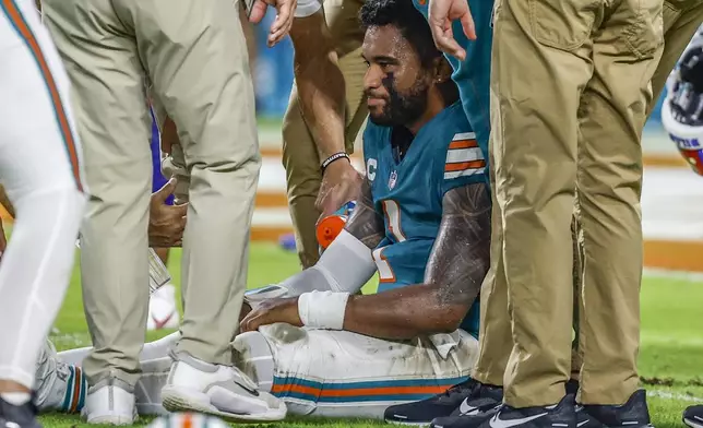 Miami Dolphins quarterback Tua Tagovailoa (1) sits on the field as he is attended to after an injury during the game against the Buffalo Bills in the second half of an NFL football game on Thursday, Sept. 12, 2024. (Al Diaz/Miami Herald via AP)