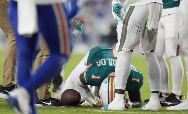 Miami Dolphins quarterback Tua Tagovailoa (1) is assisted on the field during the second half of an NFL football game against the Buffalo Bills, Thursday, Sept. 12, 2024, in Miami Gardens, Fla. (AP Photo/Rebecca Blackwell)