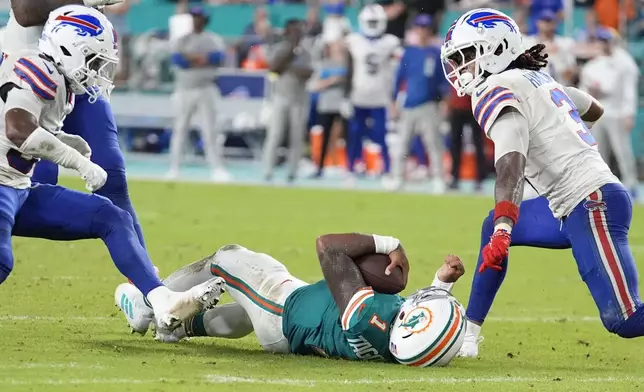 Miami Dolphins quarterback Tua Tagovailoa (1) falls in the field after colliding with Buffalo Bills safety Damar Hamlin (3) during the second half of an NFL football game, Thursday, Sept. 12, 2024, in Miami Gardens, Fla. (AP Photo/Rebecca Blackwell)