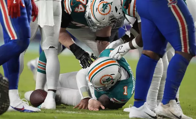 Miami Dolphins quarterback Tua Tagovailoa (1) is assisted on the field during the second half of an NFL football game against the Buffalo Bills, Thursday, Sept. 12, 2024, in Miami Gardens, Fla. (AP Photo/Rebecca Blackwell)