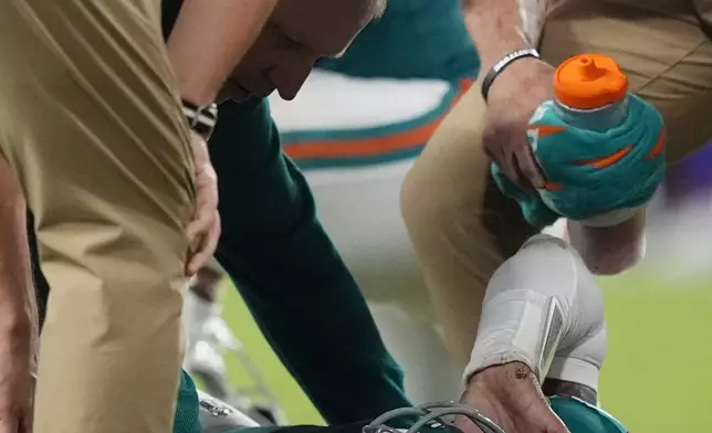 Miami Dolphins quarterback Tua Tagovailoa (1) is assisted on the field after suffering a concussion during the second half of an NFL football game against the Buffalo Bills, Thursday, Sept. 12, 2024, in Miami Gardens, Fla. (AP Photo/Rebecca Blackwell)