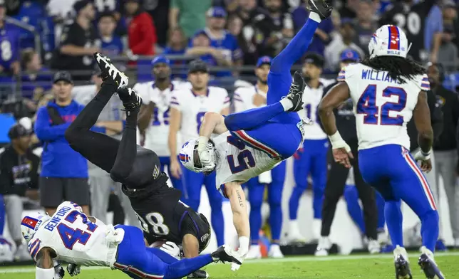 Baltimore Ravens tight end Isaiah Likely, second from left, is upended by Buffalo Bills cornerback Christian Benford (47) and linebacker Baylon Spector (54) after making a catch during the first half of an NFL football game, Sunday, Sept. 29, 2024, in Baltimore. Bills' Dorian Williams (42) looks on. (AP Photo/Nick Wass)