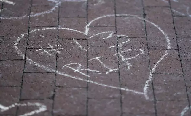 Columbus Blue Jackets fans leave chalk messages during the candlelight vigil to honor Blue Jackets hockey player Johnny Gaudreau, Thursday, Sept. 4, 2024, outside of Nationwide Arena in Columbus, Ohio. Gaudreau and his brother Matthew were killed by a motor vehicle last week while riding bicycles. (AP Photo/Joe Maiorana)