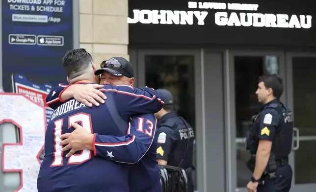 Hylas Stemen, facing, of Columbus, hugs Dave Fetzer at a memorial set up by fans for Blue Jackets hockey player Johnny Gaudreau in Columbus, Ohio, Aug. 30, 2024. Gaudreau, along with his brother Matthew, was fatally struck by a motorist while riding his bicycle on Thursday. (AP Photo/Joe Maiorana)