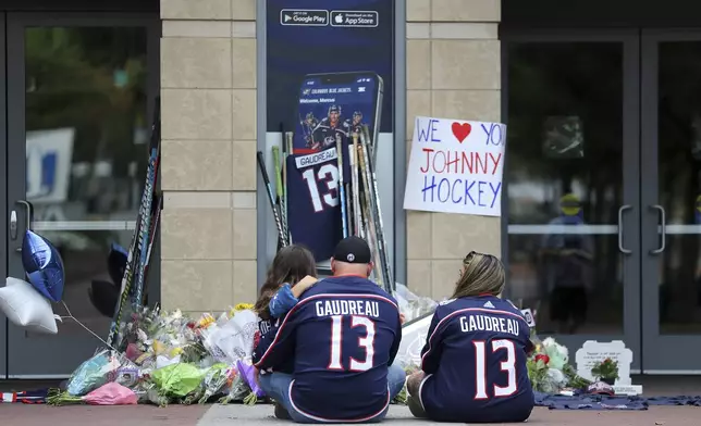 Shiloh Rivera, left, mourns with Hylas Stemen, center, and Amanda Rivera of Columbus, at a memorial set up by fans for Blue Jackets hockey player Johnny Gaudreau in Columbus, Ohio, Aug. 30, 2024. Gaudreau, along with his brother Matthew, was fatally struck by a motorist while riding his bicycle on Thursday. (AP Photo/Joe Maiorana)