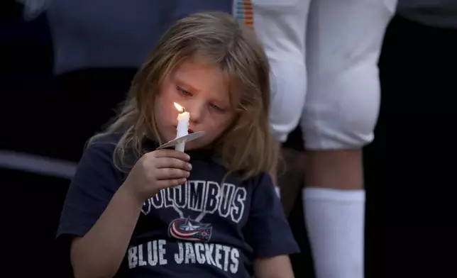 Columbus Blue Jackets fan Scarlett Well, has a moment of silence during the candlelight vigil to honor of Blue Jackets hockey player Johnny Gaudreau, outside of Nationwide Arena in Columbus, Ohio, Thursday, Sept. 4, 2024. Gaudreau and his brother Matthew were killed by a motor vehicle last week while riding bicycles. (AP Photo/Joe Maiorana)