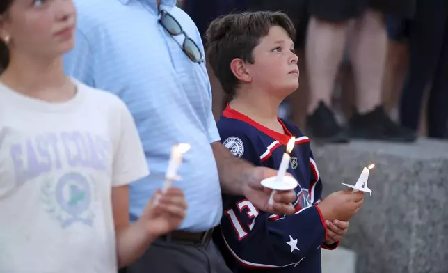 Blue Jackets fan Hudson Saad of Columbus, has a moment of silence during the candlelight vigil to honor Columbus Blue Jackets hockey player Johnny Gaudreau, outside of Nationwide Arena in Columbus, Ohio, Thursday, Sept. 4, 2024. Gaudreau and his brother Matthew were killed by a motor vehicle last week while riding bicycles. (AP Photo/Joe Maiorana)