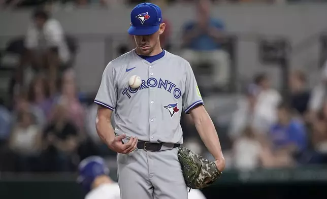 Toronto Blue Jays starting pitcher Chris Bassitt tosses the ball as he stands on the mound after walking Texas Rangers' Wyatt Langford in the fourth inning of a baseball game in Arlington, Texas, Tuesday, Sept. 17, 2024. (AP Photo/Tony Gutierrez)