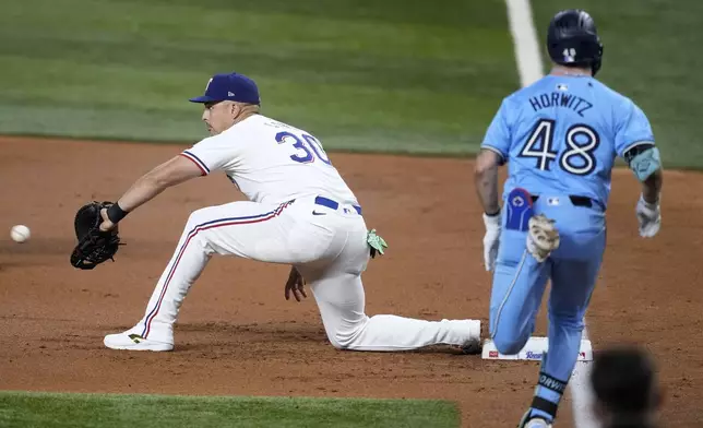 Texas Rangers first baseman Nathaniel Lowe (30) reaches out for the throw to the bag to complete the ground out by Toronto Blue Jays' Spencer Horwitz (48) in the second inning of a baseball game in Arlington, Texas, Wednesday, Sept. 18, 2024. (AP Photo/Tony Gutierrez)