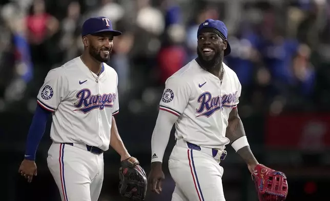 Texas Rangers' Marcus Semien, left, and Adolis Garcia walk off the field after their team's win against the Toronto Blue Jays in a baseball game in Arlington, Texas, Wednesday, Sept. 18, 2024. (AP Photo/Tony Gutierrez)