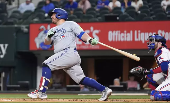 Toronto Blue Jays' Alejandro Kirk follows through on a run-scoring double as Texas Rangers' Jonah Heim, right, looks on in the first inning of a baseball game in Arlington, Texas, Tuesday, Sept. 17, 2024. (AP Photo/Tony Gutierrez)