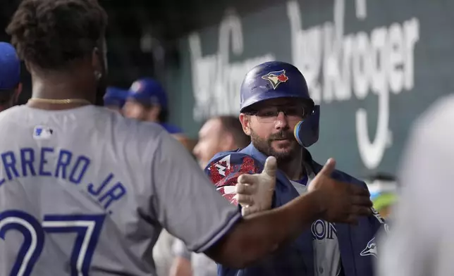 Toronto Blue Jays' Vladimir Guerrero Jr. (27) and Davis Schneider, right, celebrate after Schneider hit a two-run home run against the Texas Rangers in the fifth inning of a baseball game in Arlington, Texas, Tuesday, Sept. 17, 2024. (AP Photo/Tony Gutierrez)