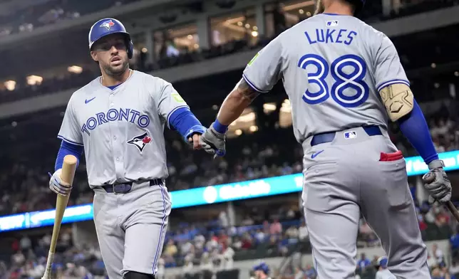 Toronto Blue Jays' George Springer, left, and Nathan Lukes (38) celebrate after Springer scored on a Alejandro Kirk double in the first inning of a baseball game against the Texas Rangers in Arlington, Texas, Tuesday, Sept. 17, 2024. (AP Photo/Tony Gutierrez)